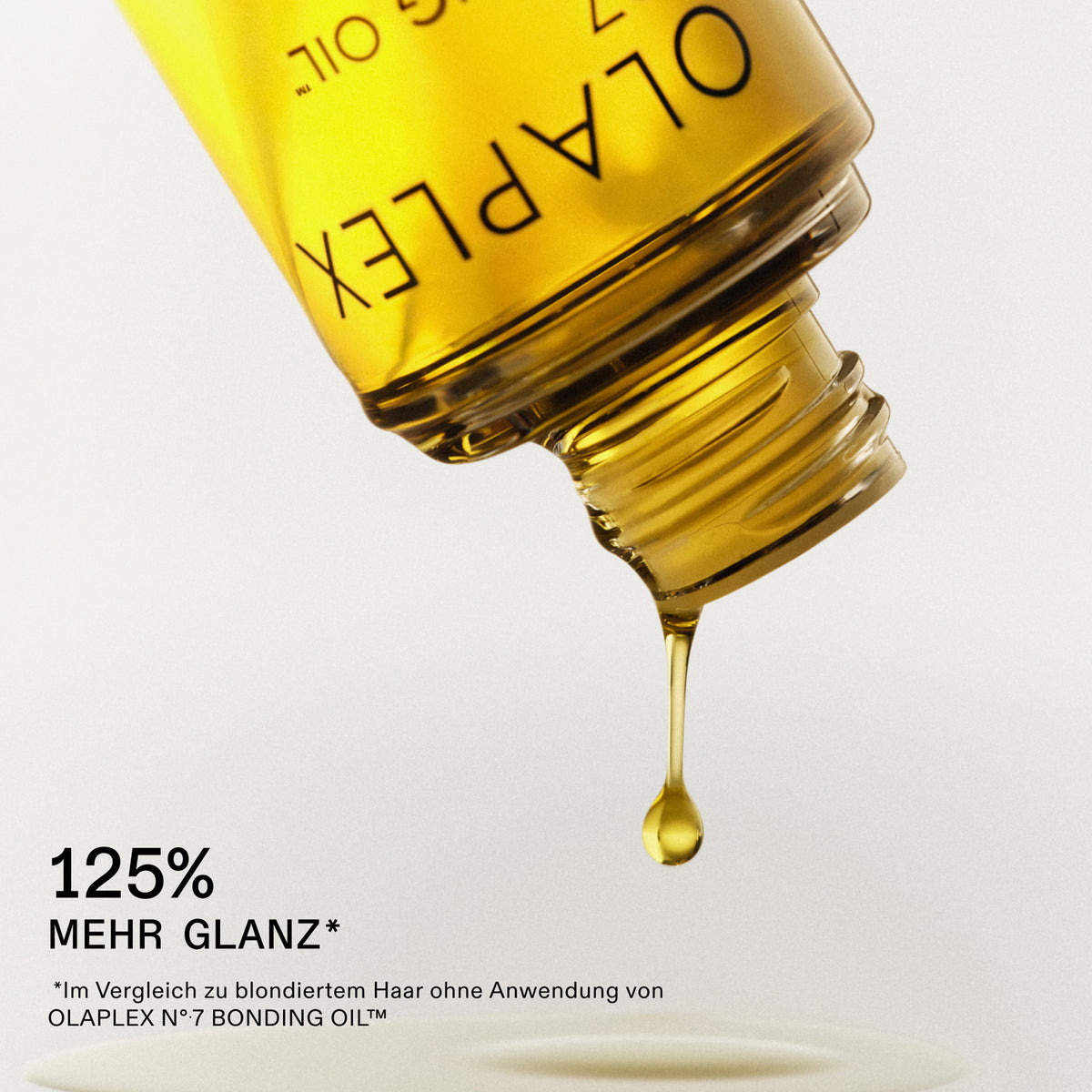Nahaufnahme einer Flasche N°7 Bonding Oil 30ml, aus dem Haaröl tropft; darunter Text: "125% mehr Glanz."