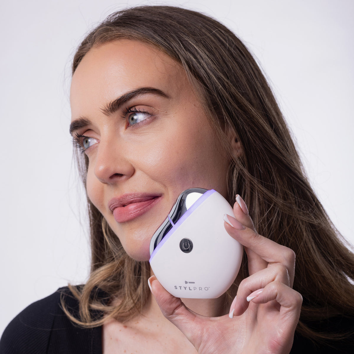 Frau massiert sanft ihr Kinn mit dem weißen STYLPRO Gua Sha, der an der silbernen Fläche ein dezentes violettes Licht ausstrahlt.