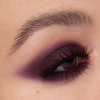 Nahaufnahme eines Auges mit kräftigem, dunkelviolettem Smokey-Lidschatten und einer betonten Augenbraue, kreiert mit Cupid’s Arrow Longwear Stylo.