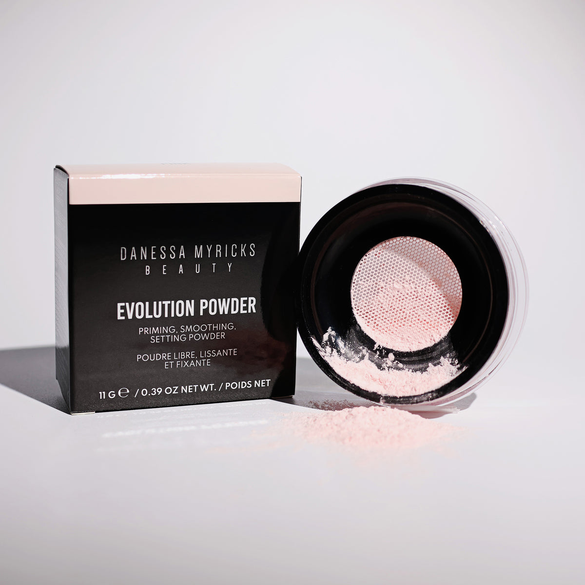 Verpackung und offener Tiegel Evolution Powder Pink stehen nebeneinander auf einer weißen Fläche.
