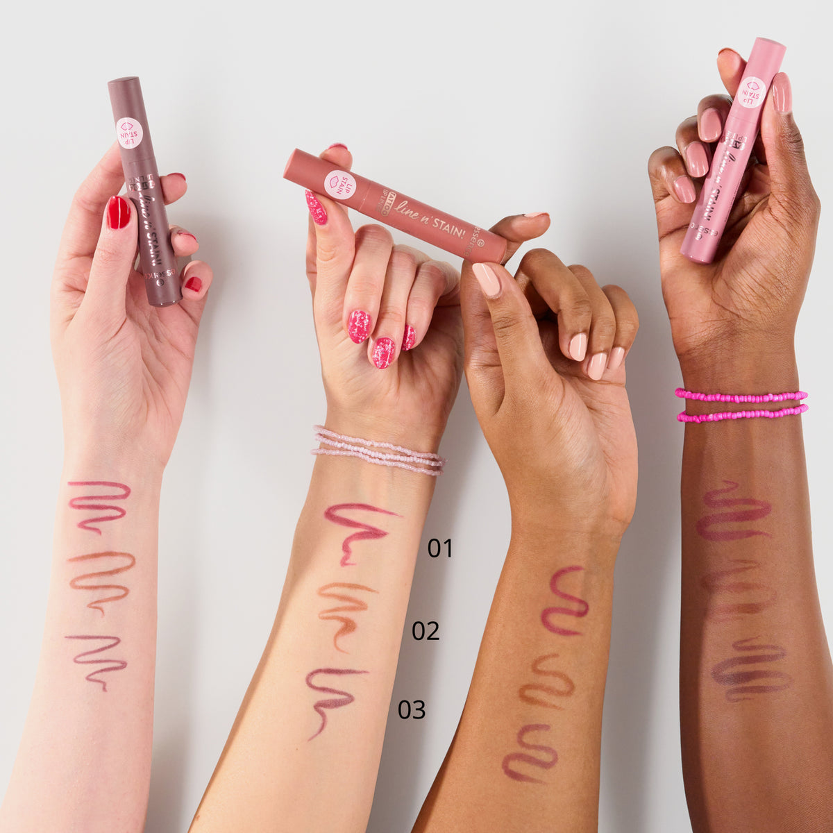 Vier Arme unterschiedlicher Hautfarbe zeigen Lippenstiftmuster auf ihren Armen, jede hält einen anderen Farbton des Line n‘ STAIN! TATTOO LIP LINER.
