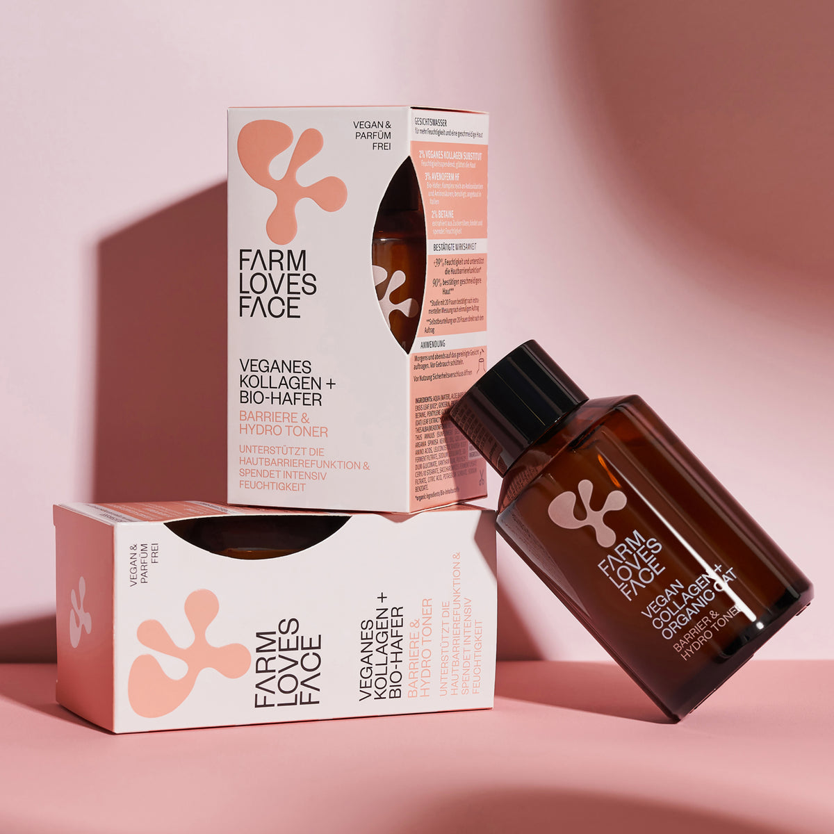 Eine braune Flasche und zwei Verpackungen des Vegan Collagen + Organic Oat Barrier & Hydro Toner vor einem rosa Hintergrund.