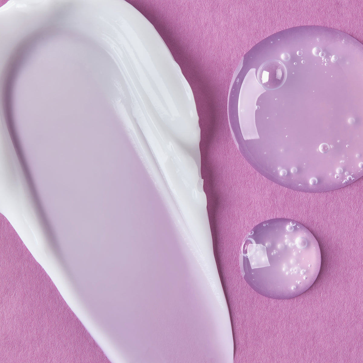 Weißer Creme-Swatch und zwei klare Tropfen Collagen Peptide Hydra Ampoule auf rosa Hintergrund.