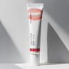 Auf einer weißen Fläche steht eine Tube getönter Lipgloss SPF50 mit einem roten Lippenstift-Kussabdruck auf der Tube.