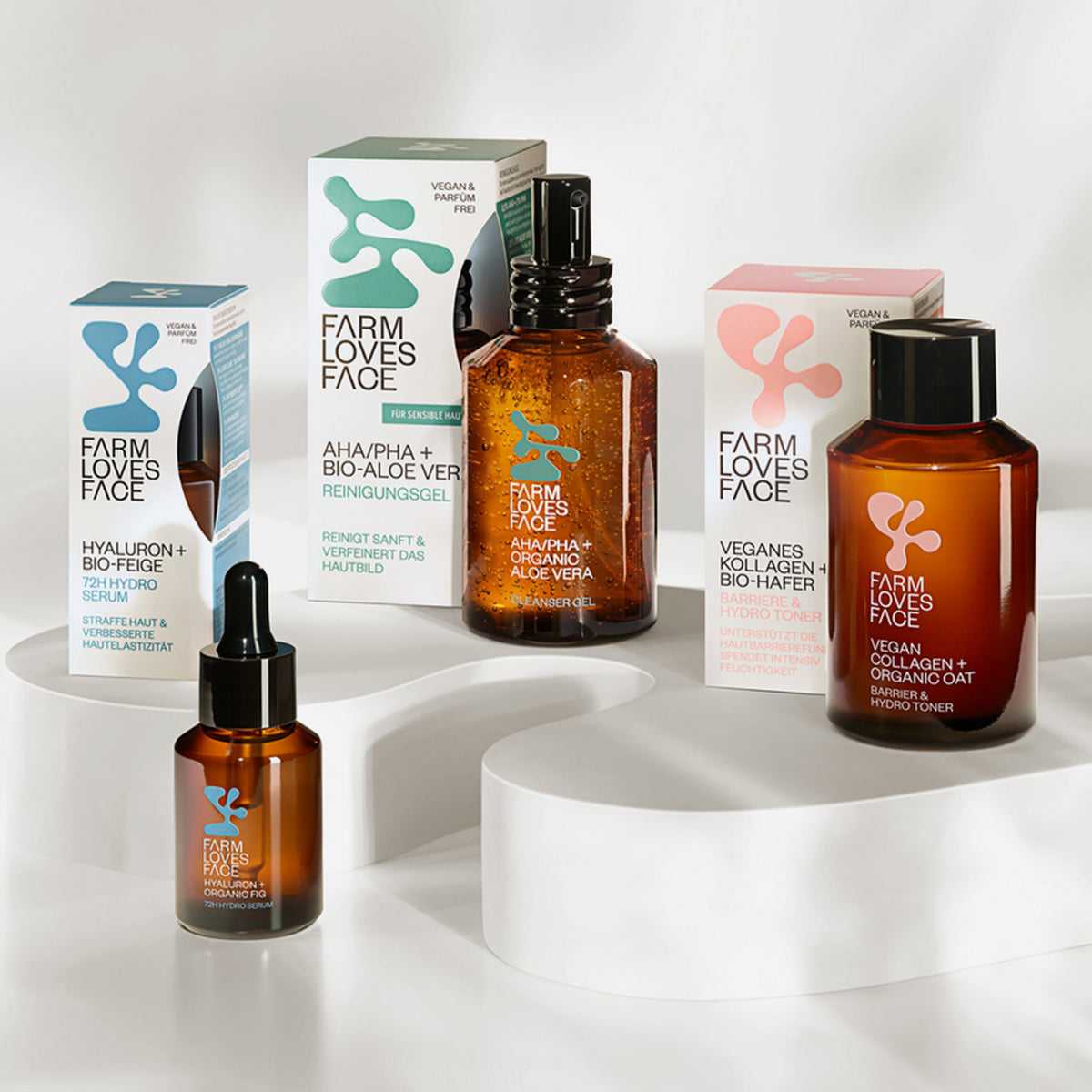 Mehrere Produkte des Farm Loves Face Skincare-Reihe auf einer weißen geschwungenen Plattform.