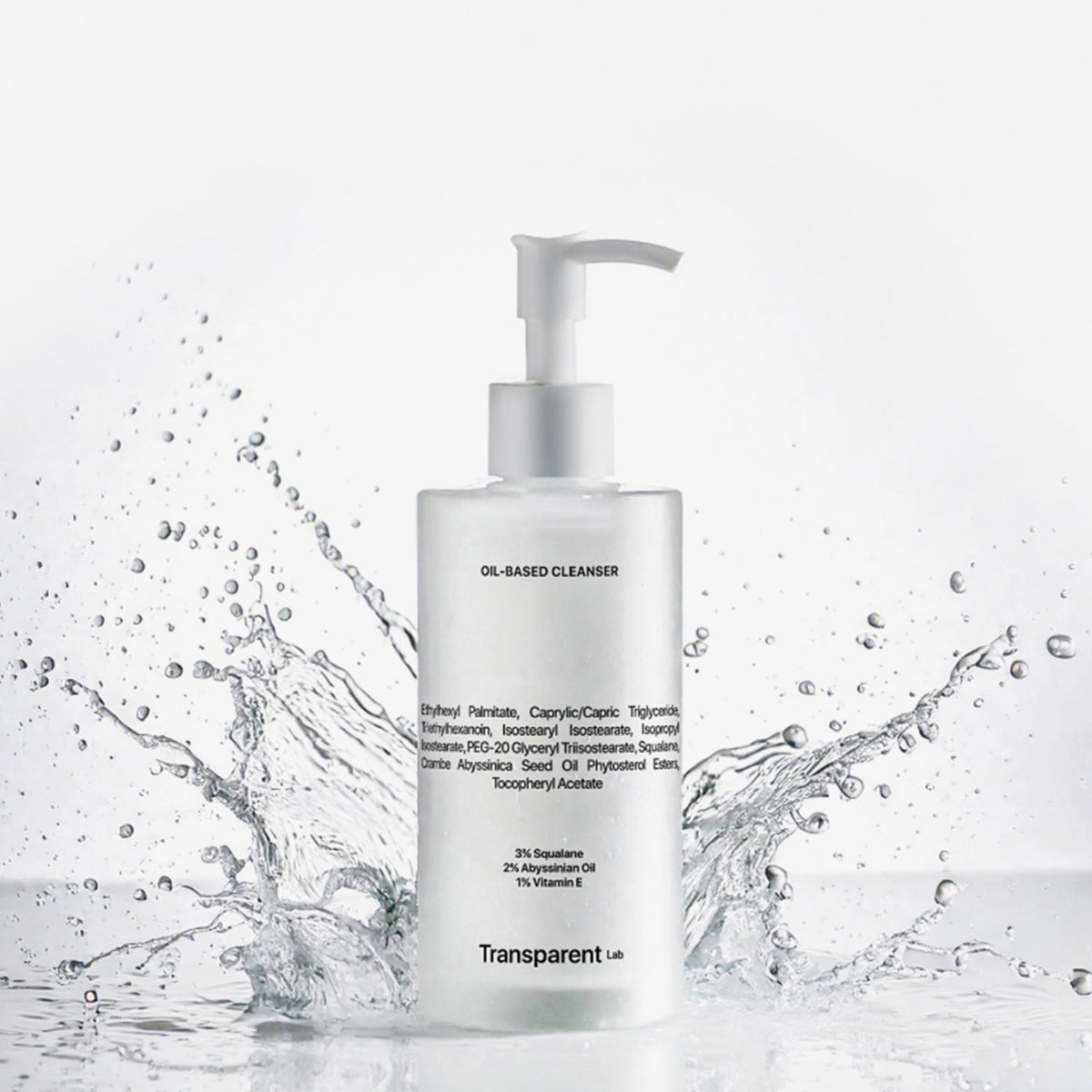 Eine Pumpflasche Oil-Based Cleanser mit der Aufschrift vor einem weißen Hintergrund mit spritzendem Wasser.