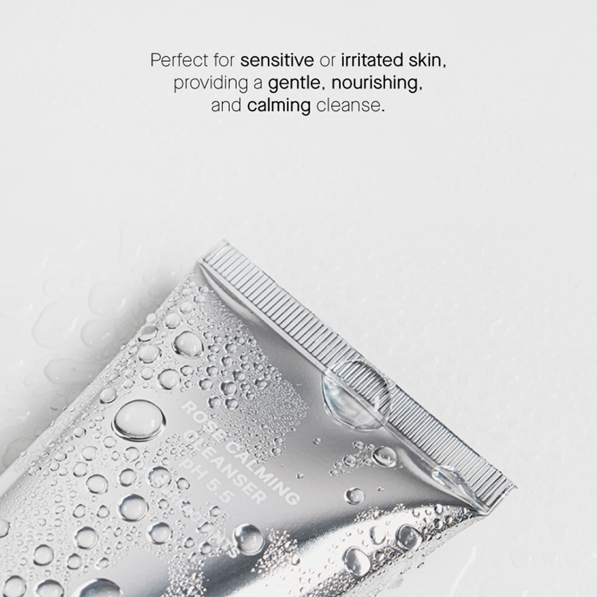 Eine Tube Rose Calming Cleanser pH 5,5 liegt auf einer hellen Oberfläche mit Wassertropfen. Es wird oben als für empfindliche Haut geeignet beschrieben.