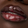 Nahaufnahme der Lippen einer Person mit dunkler Haut mit dem Glossin‘ Glow Tinted Lip Oil 030.
