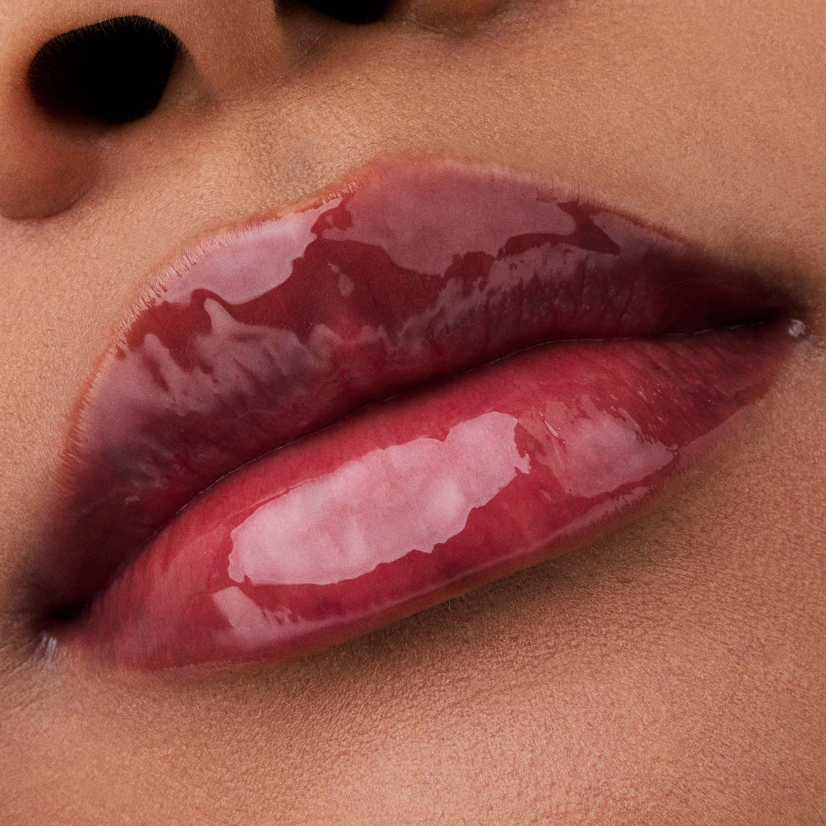 Nahaufnahme der Lippen einer Person mit brauner Haut mit dem Glossin‘ Glow Tinted Lip Oil 030.