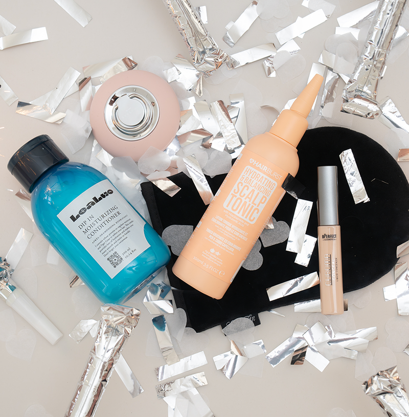 Beautyprodukte von LeaLuo, HAIRBURST und BPerfect auf grauer Oberfläche mit silbernem Konfetti.