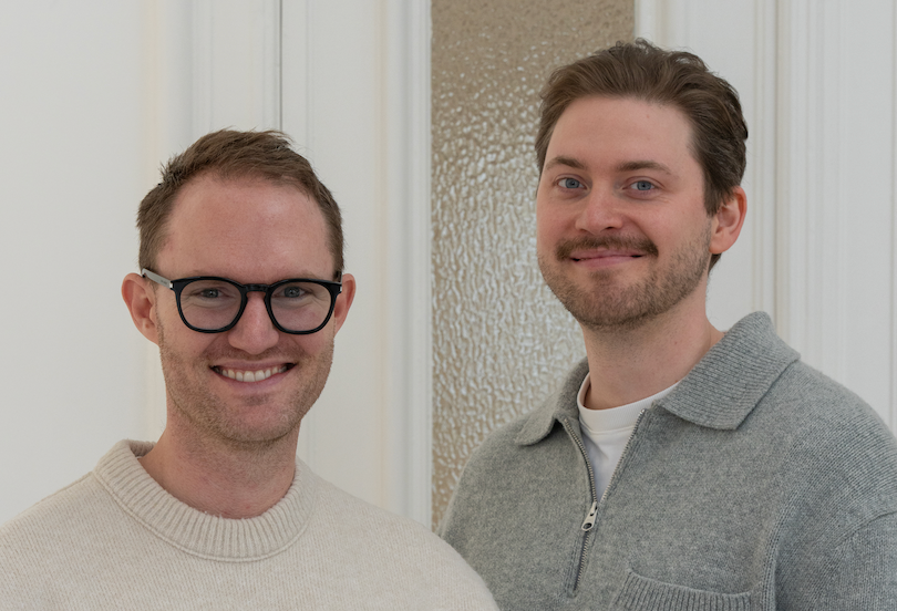 PURISH-Gründer Philipp und Lucas in hellen Strickpullovern stehen nebeneinander und lächeln in die Kamera.