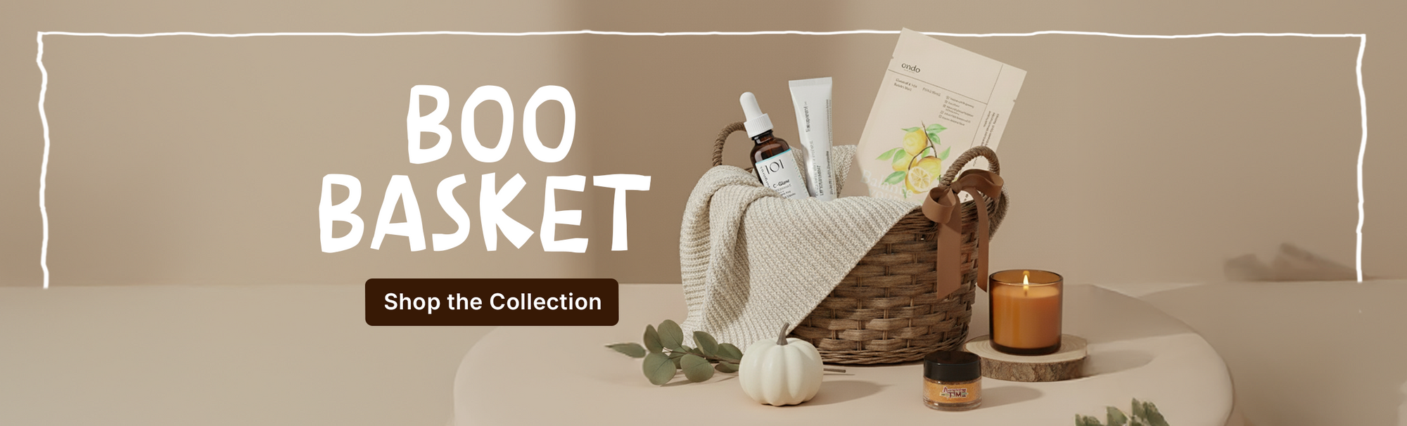Basket with beauty products, blanket, candle and pumpkin on beige background, text 'Boo Basket'.