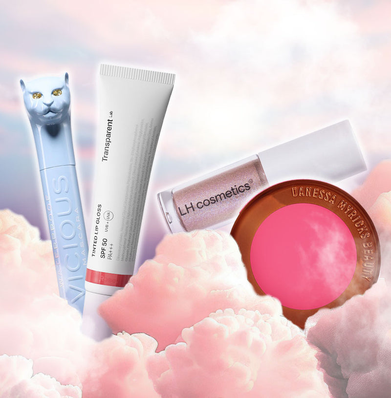 Vier Beauty-Produkte: eine hellblaue Mascara mit Katzenkopf, eine weiße Tube Lip Gloss, ein LH cosmetics Lipgloss und ein pinker Danessa Myricks Blush – schweben vor rosa Wolken.