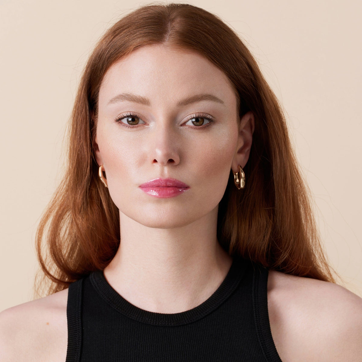 Frau mit langen roten Haaren präsentiert das Glossin' Glow Tinted Lip Oil 010.