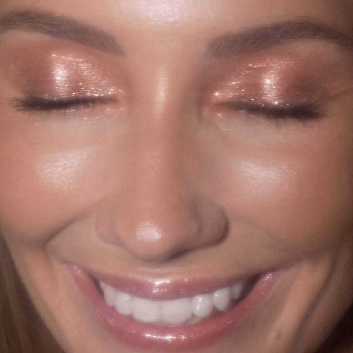 Eine Frau mit geschlossenen Augen präsentiert den schimmernden pfirsichfarbenen Lidschatten Sparkl Flirt von LH Cosmetics.