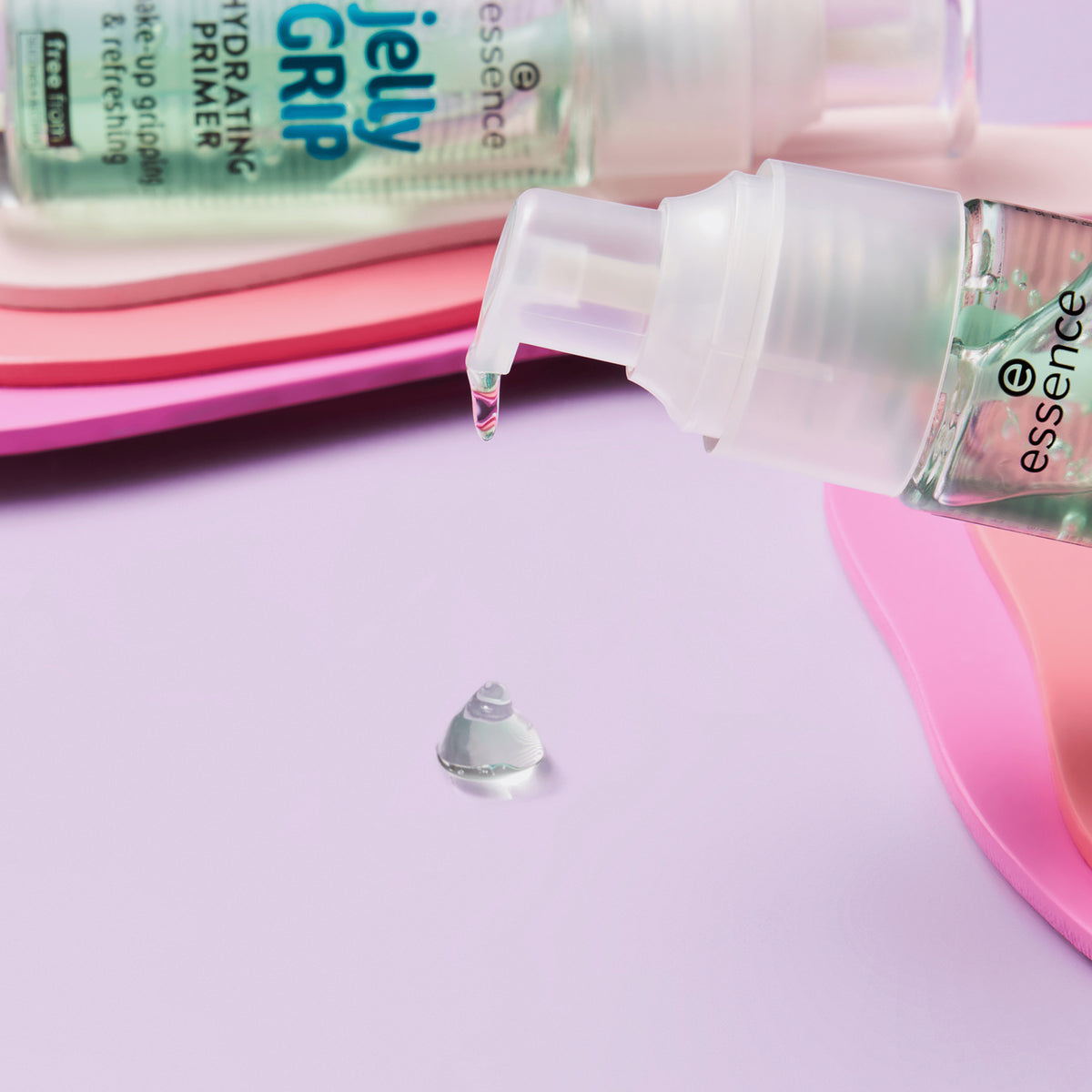 Nahaufnahme der Pumpe des essence jelly GRIP HYDRATING PRIMER mit Gel-Tropfen auf rosa-lila Untergrund.