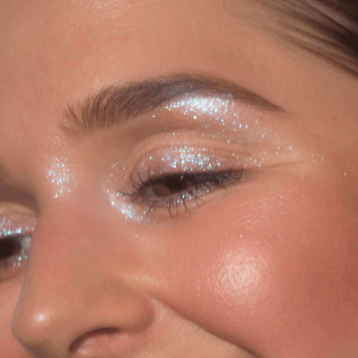 Nahaufnahme des Gesichts einer Frau mit opal-blau glitzerndem Lidschatten Sparkl Blink von LH Cosmetics.