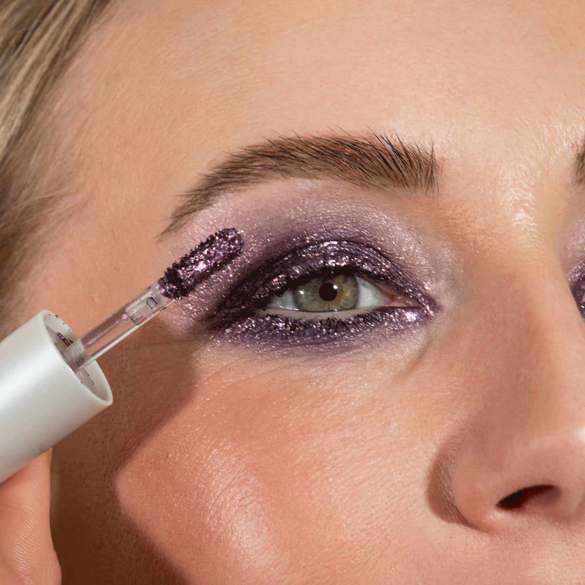 Nahaufnahme des Gesichts einer Frau mit lila glitzerndem Lidschatten Sparkl Magic von LH Cosmetics.