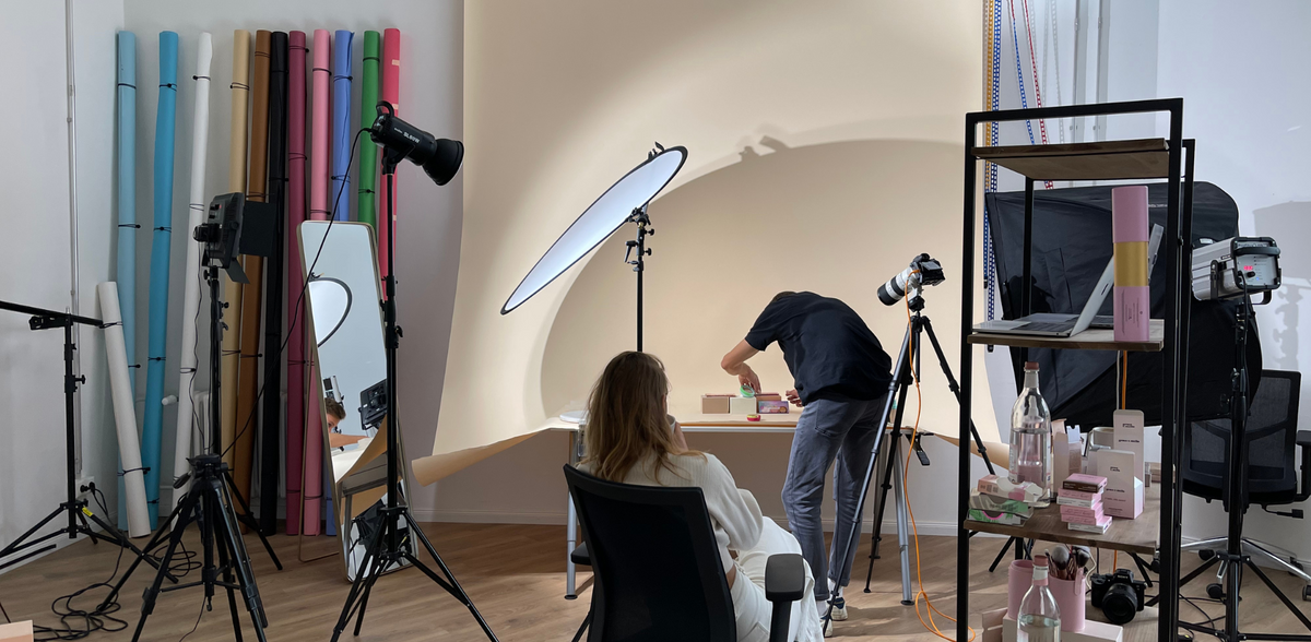 Fotostudio im PURISH GmbH Lager mit bunten Hintergründen, Lichttechnik und zwei Personen beim Produktshooting an einem Tisch.