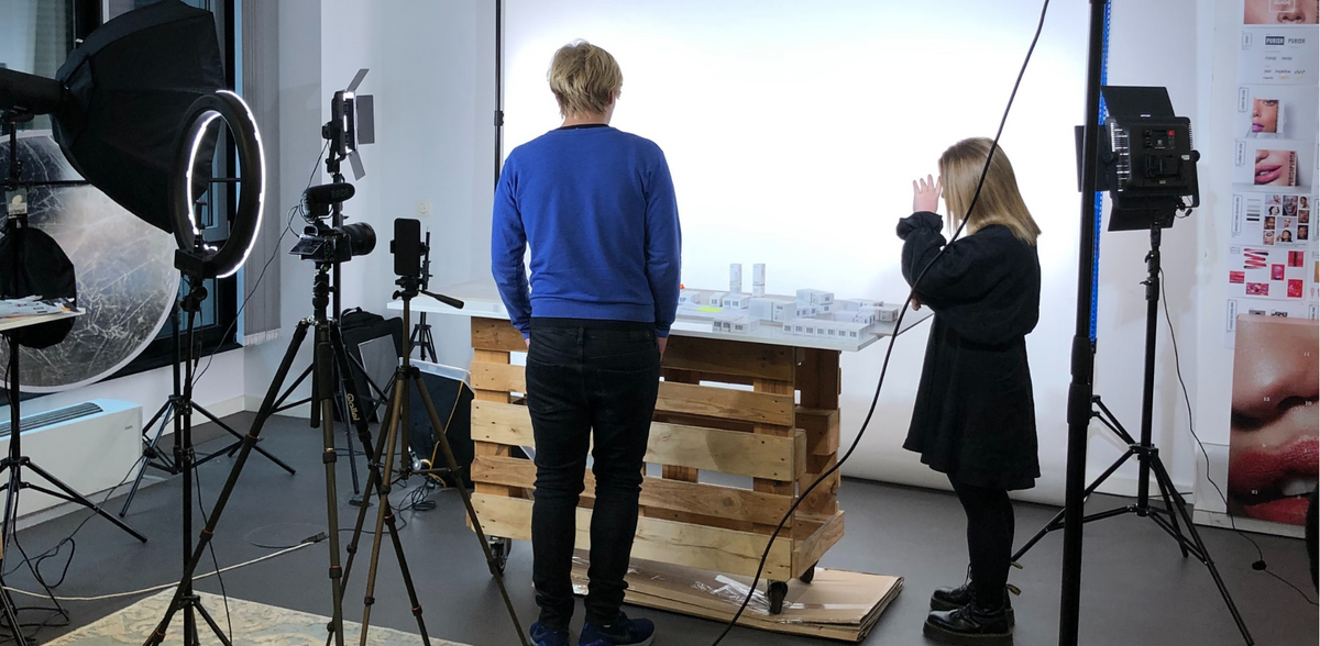 Zwei Personen in einem Fotostudio-Setup im PURISH GmbH-Office, mit Kameras, Lichtboxen und Produkten auf Holztisch vor weißem Hintergrund.