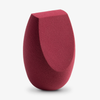 Der Flawless Precision Makeup Sponge mit flacher Kante und abgerundeter Basis in Rot steht aufrecht auf einem weißen Hintergrund.