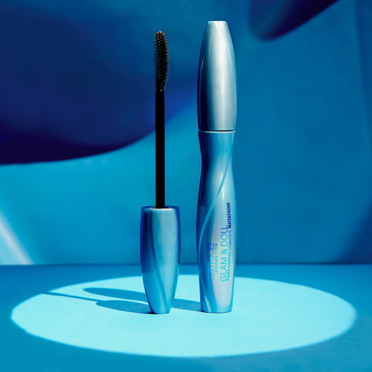 Blaue Tube Catrice Glam & Doll False Lashes Mascara Waterproof 010 im Spotlight vor blauem Hintergrund.