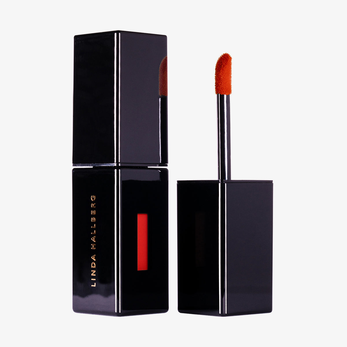 Schwarze rechteckige Lipgloss Tube Velvet Couture in Orange Red von LH Cosmetics neben offenem Applikator mit knallrotem Produkt.