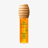 Eine Flasche NUXE Honey Lip Care Rêve de Miel mit einem Verschluss in Form einer Honiglöffel.
