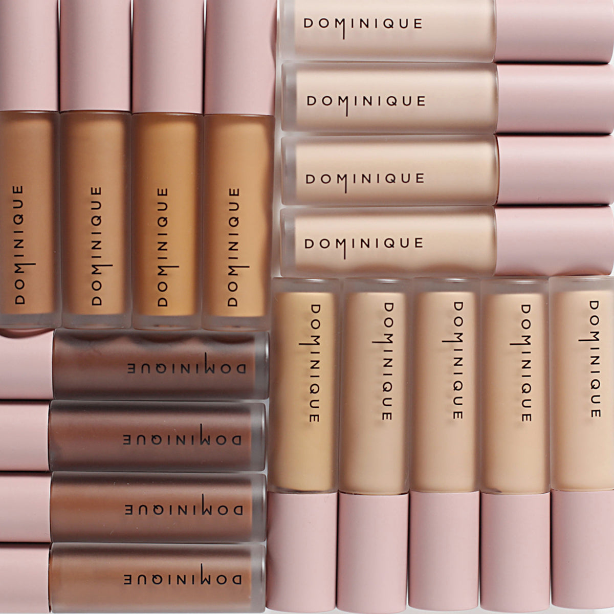 Mehrere Wide Awake Full Coverage Concealer von Dominique Comsetics in verschiedenen Hauttönen, symmetrisch angeordnet, mit rosa Verschlüssen.