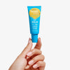 Eine Hand hält eine Tube Lip Balm SPF 50+ Toasted  vor weißem Hintergrund