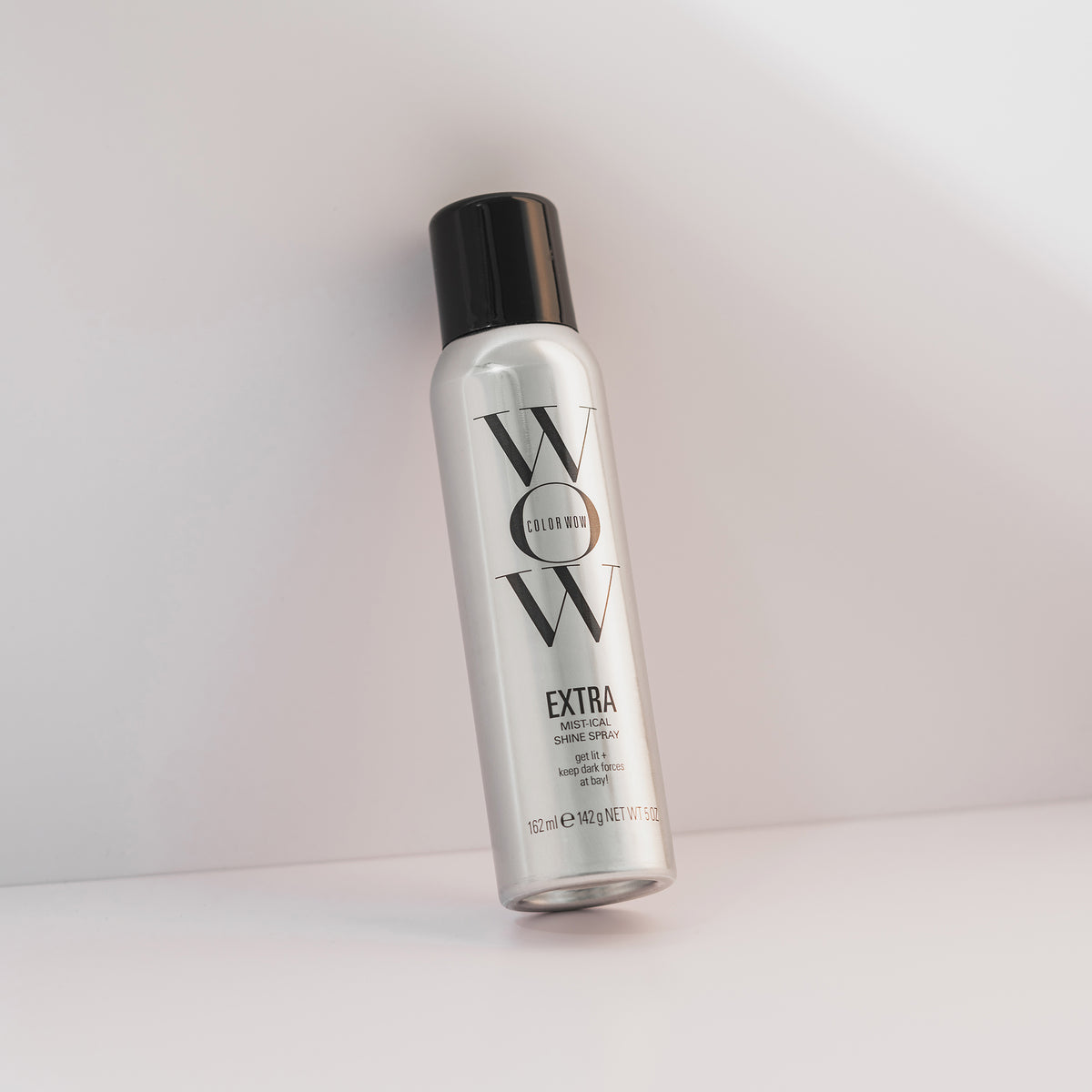 Eine Dose Extra Shine Spray mit schwarzer Kappe steht vor einem hellen Hintergrund.