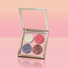 Geöffnete NABLA „Miami Lights“ Glitter Palette mit vier Glitzertönen, aufrecht platziert vor einem glänzenden Hintergrund in Pfirsich-Rosa-Verlauf.