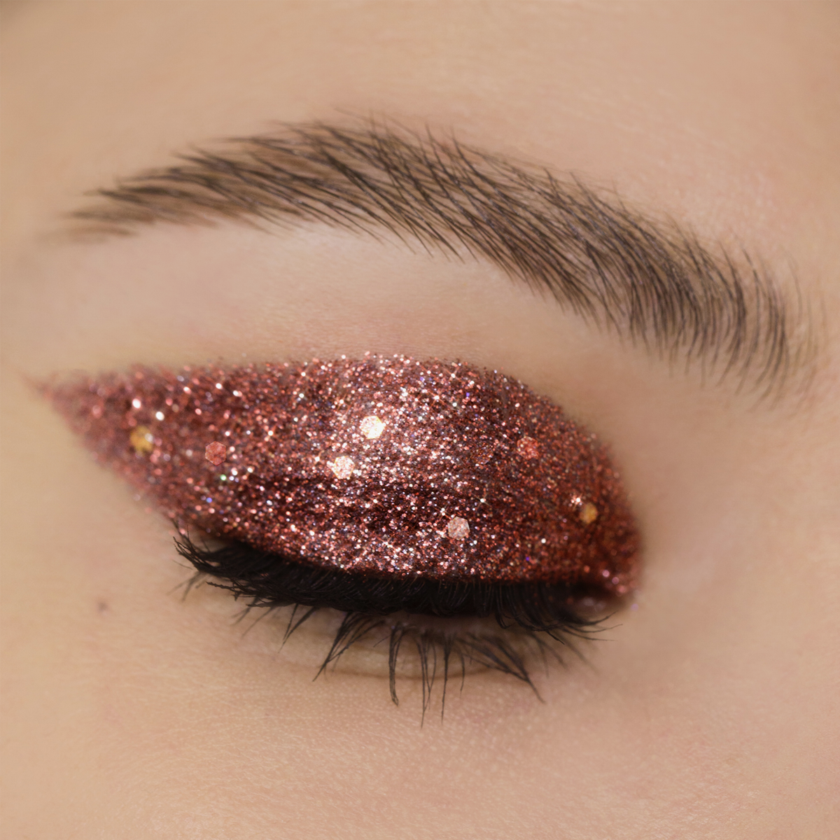 Geschlossene Augen mit kräftigem, roségoldenem Glitzerlidschatten aus der Miami Lights Glitter Palette.