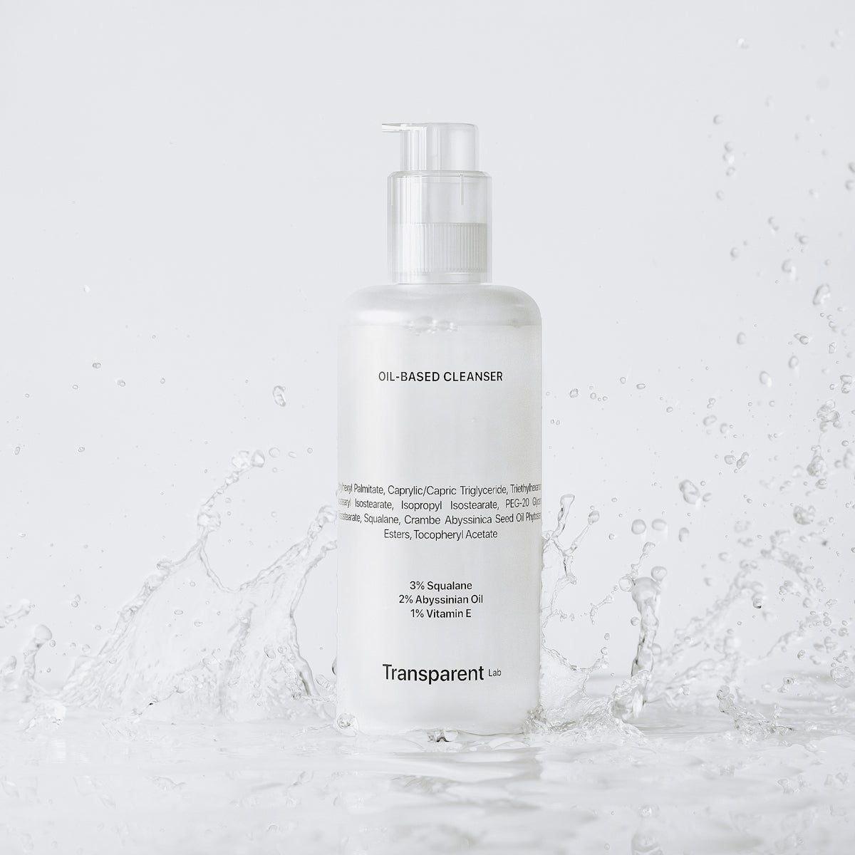 Transparent Lab Oil-based Cleanser vor weißem Hintergrund, in einer Pfütze aus der Wasser spritzt