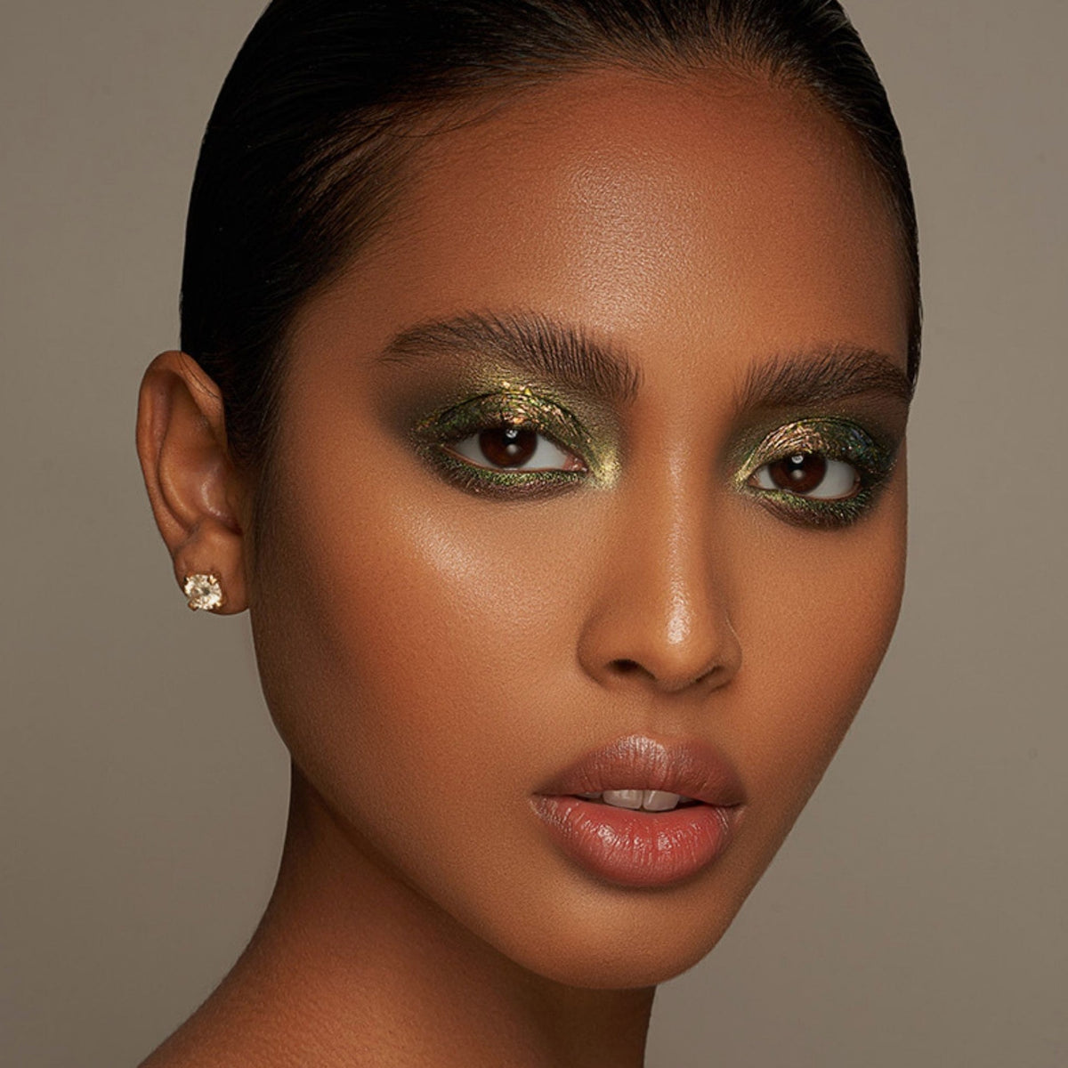 Person mit geschlossenen Augen und mittelbraunem Hautton präsentiert schimmernden, irisierenden Make-up-Look mit den Infinite Chrome Flakes.