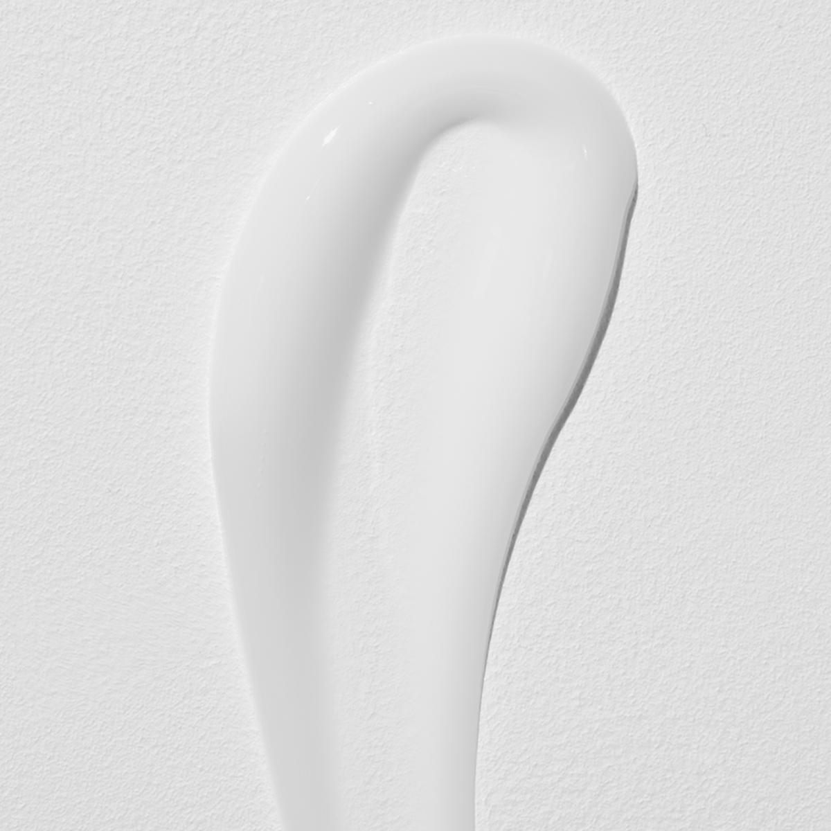 Ein glatter milchiger Swatch der Advanced Snail 92 All In One Cream auf einer strukturierten weißen Oberfläche.