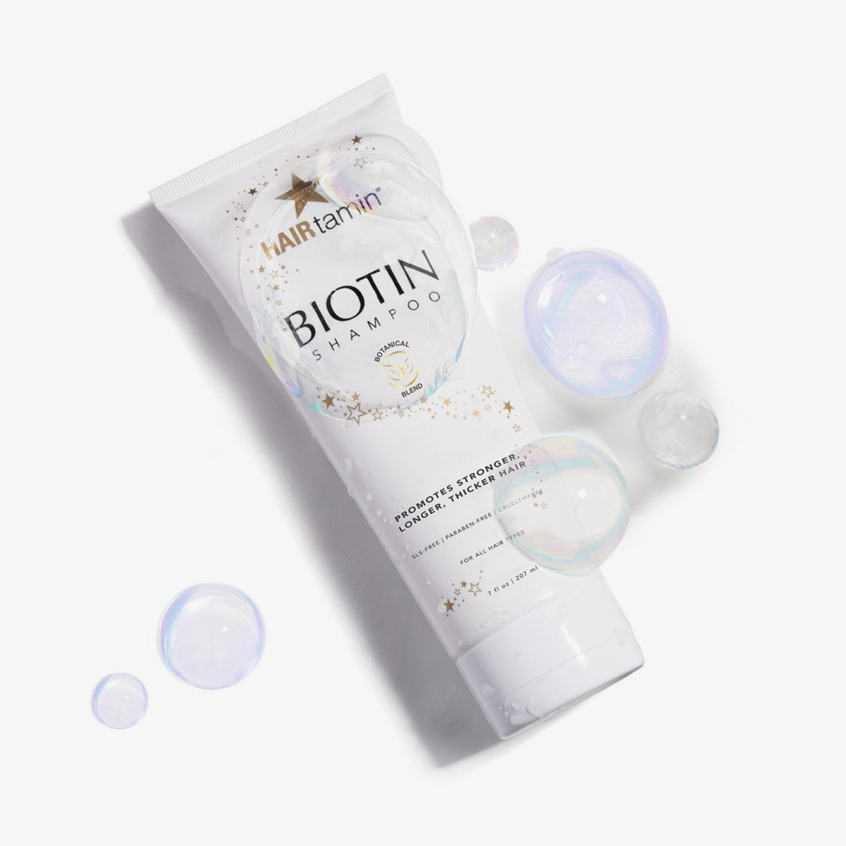 Eine Packung Biotin Shampoo von HAIRtamin vor weißem Hintergrund mit Seifenblasen