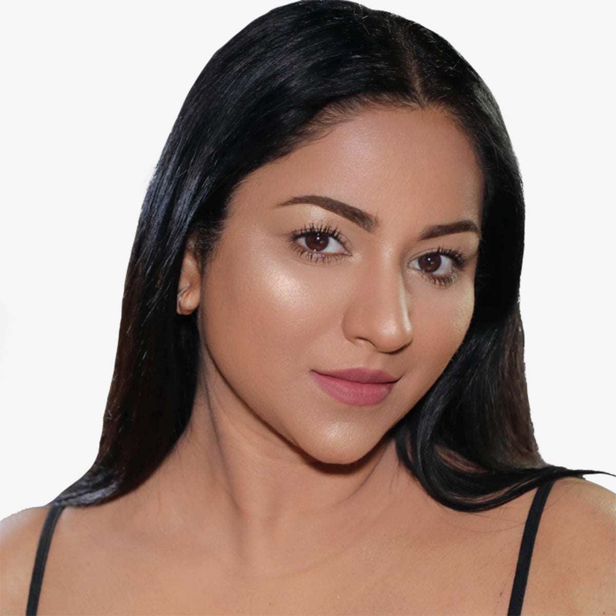 Eine Frau mit langem dunklem Haar und einem leichten Lächeln präsentiert den Liquid Highlighter von OFRA Cosmetics vor einem weißen Hintergrund.