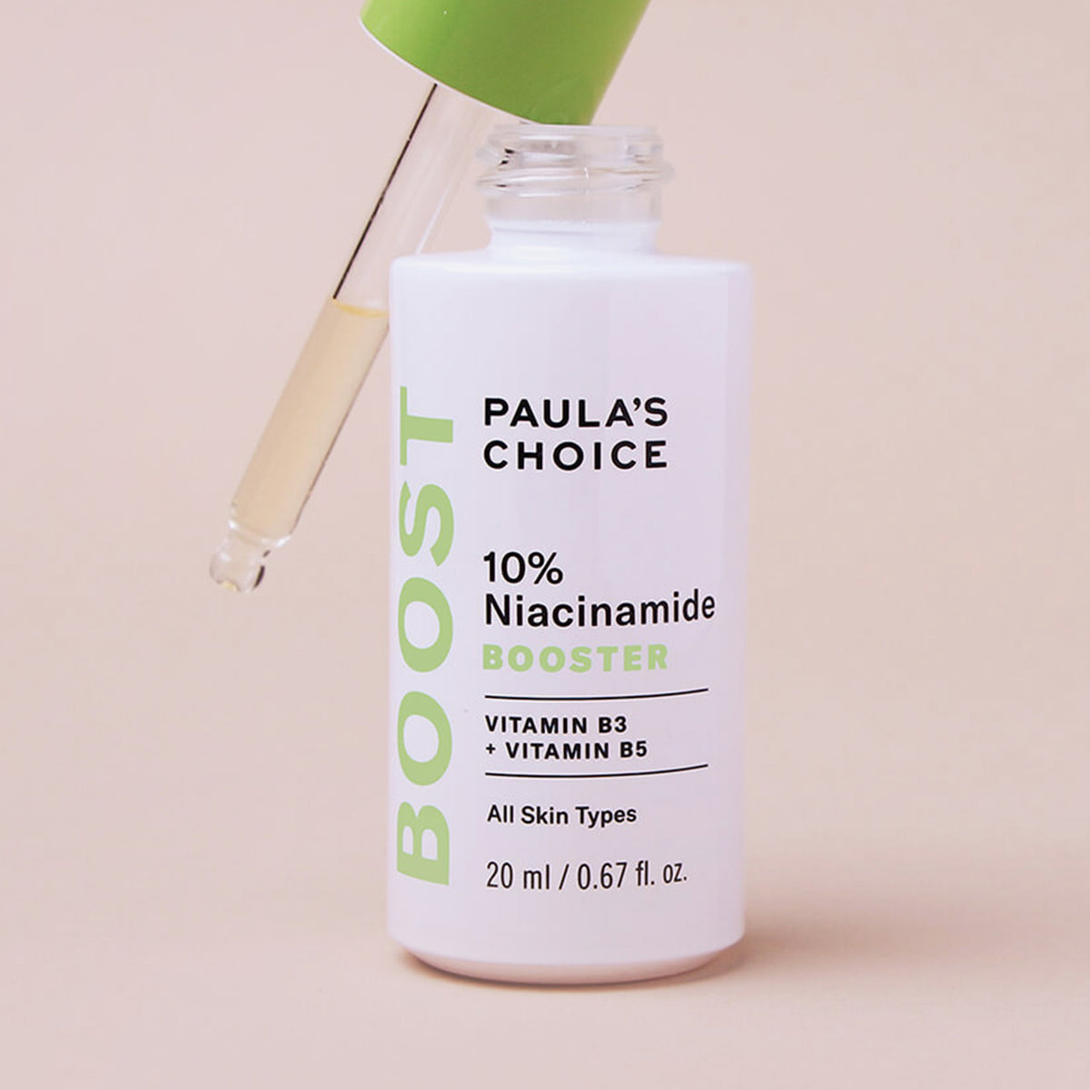 Weiße Flasche des Paula’s Choice 10% Niacinamide Boosters mit grüner Pipette, gefüllt mit leicht gelblicher Flüssigkeit, vor beigem Hintergrund.