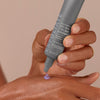 Eine Hand drückt das 25 % AHA + 2 % BHA Exfoliant Peel, ein violettes Gel, aus einer Tube auf den Handrücken der anderen Hand.