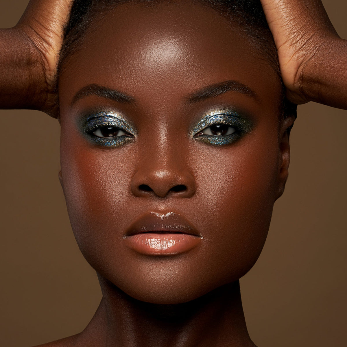 Person mit dunklem Hautton präsentiert schimmernden, irisierenden Make-up-Look mit den Infinite Chrome Flakes.