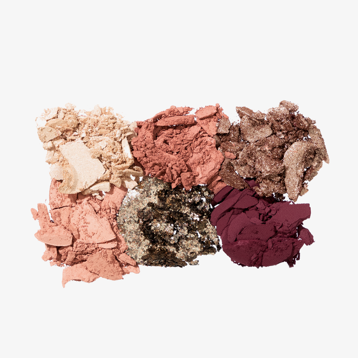 Zerkleinerte Farbtöne aus der Unconditional-Palette – Beige, Rosa, Braun, Pfirsich, Gold und Pflaume – verstreut auf einem weißen Hintergrund.