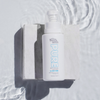 Eine strukturierte Oberfläche mit einer weißen Flasche Pure Tanning Face Mist von Bondi Sands, umgeben von plätscherndem Wasser