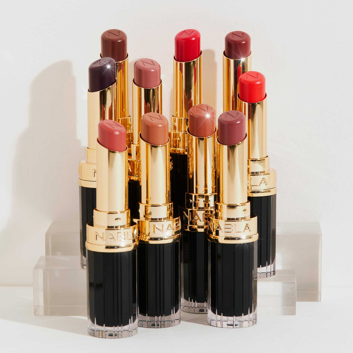 Alle zehn Farben des Beyond Jelly Lipsticks aufgereiht – jede Nuance in offener gold-schwarzer Hülse stilvoll präsentiert.