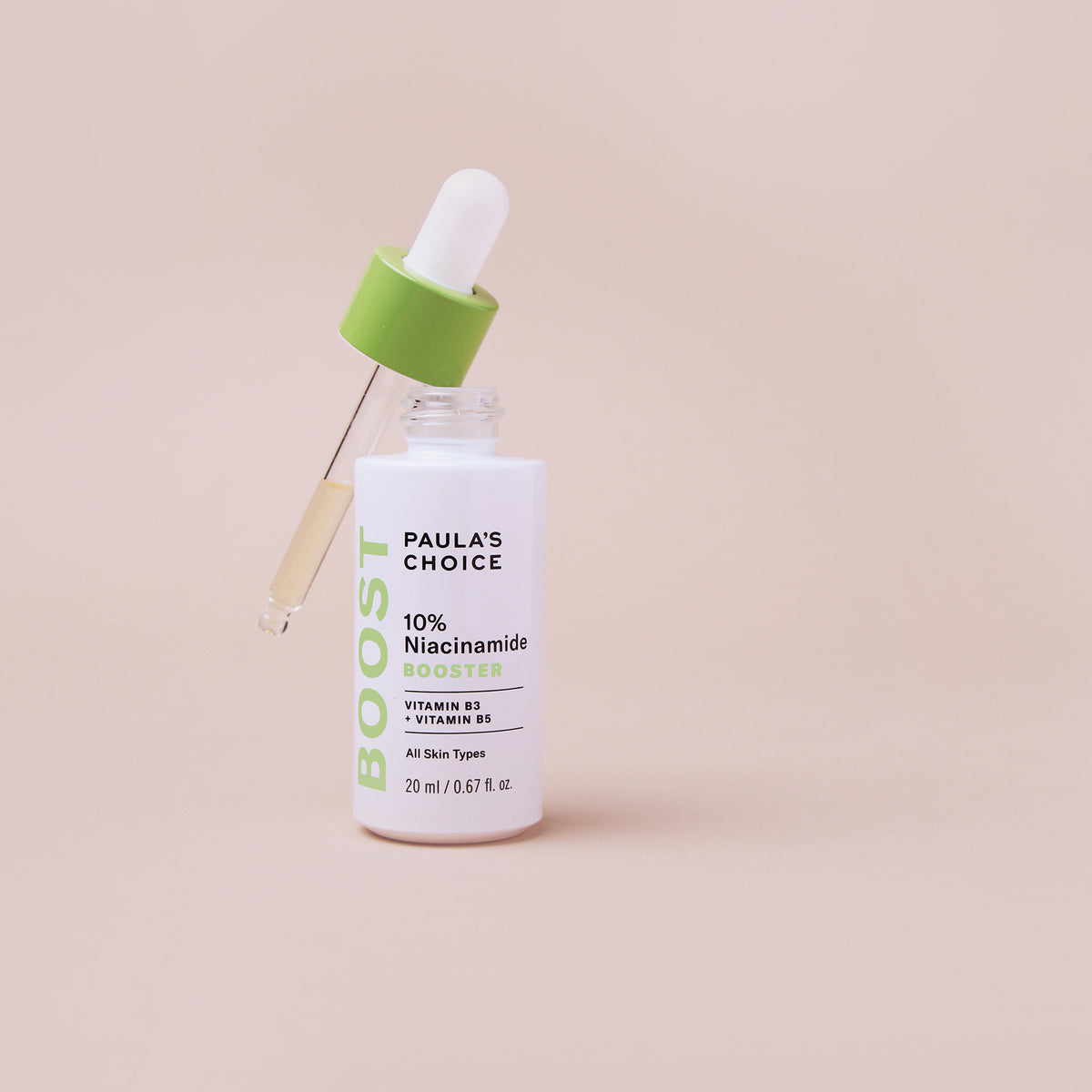Weiße Flasche des Paula’s Choice 10% Niacinamide Boosters mit grüner Pipette, gefüllt mit leicht gelblicher Flüssigkeit, vor beigem Hintergrund.