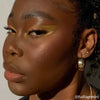 Eine Person mit auffälligem goldenen Augen-Make-up aus der 16-Farben-Lidschattenpalette „Lost in Los Angeles“