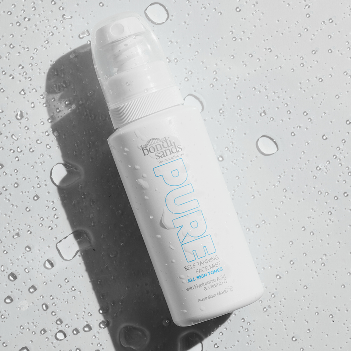 Pure Tanning Face Mist von Bondi Sands mit Wassertropfen auf einer feuchten Oberfläche