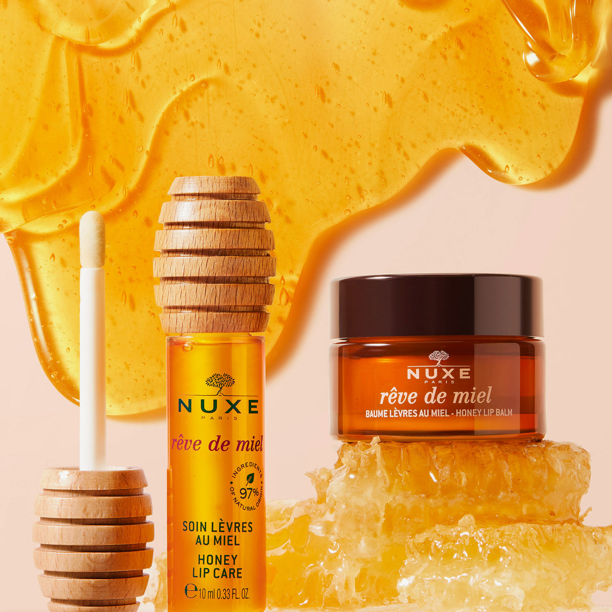 NUXE Honey Lip Care Rêve de Miel ist mit einem Honiglöffel und einer Honigwabe abgebildet, die auf einem Hintergrund aus geschmolzenem Honig präsentiert wird.