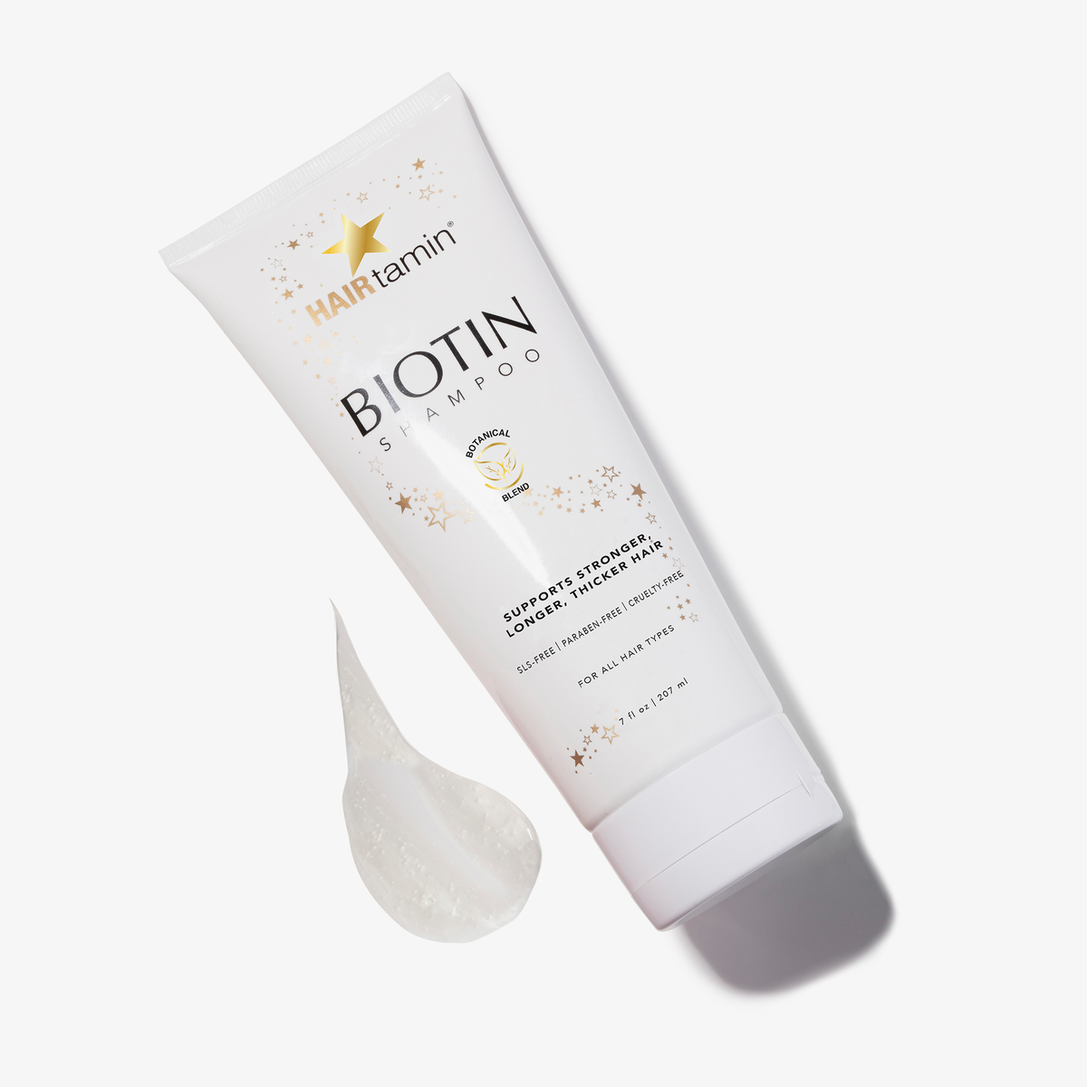 Eine Packung Biotin Shampoo von HAIRtamin vor weißem Hintergrund neben einem Fleck des Shampoos