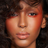 Eine Frau mit kräftigem orangefarbenem Lidschatten und Rouge, glänzenden Lippen und voluminösem lockigem Haar, kreiert mit der Waterproof Cream Palette.